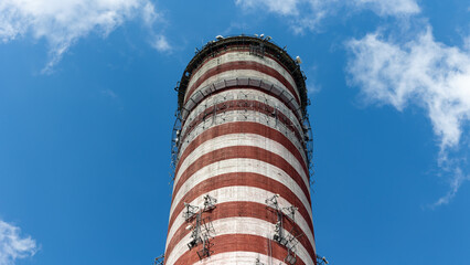 A mobile phone antennas installed on top of a tall power plant chimney. Object against the blue sky...