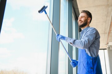 Young man cleaning window in office