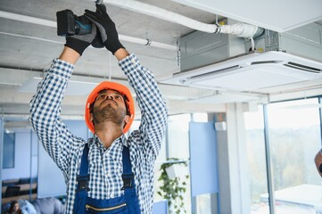 Professional technician maintaining modern air conditioner indoors. Space for text