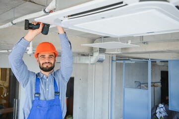 technician service checking and repairing air conditioner indoors