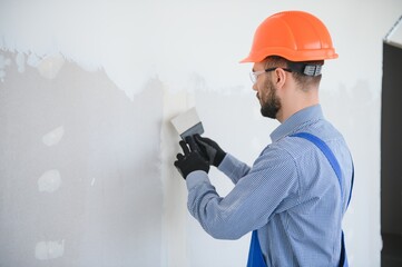 man drywall worker or plasterer sanding and smoothing a plasterboard walls with stucco using a...
