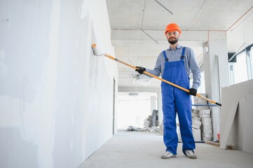 Painter in uniform paints the wall.