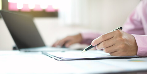 Fototapeta premium The businessman hand sits at their desks and calculates financial graphs showing the results of their investments planning the process of successful business growth