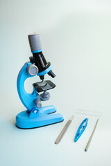 Children's toy microscope on a light blue background. An exact copy of a professional microscope with illumination and accessories for studying the world around. Template for inserting text