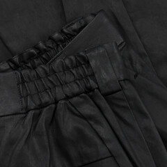 Detail of a black waxed trouser belt with loop and pocket