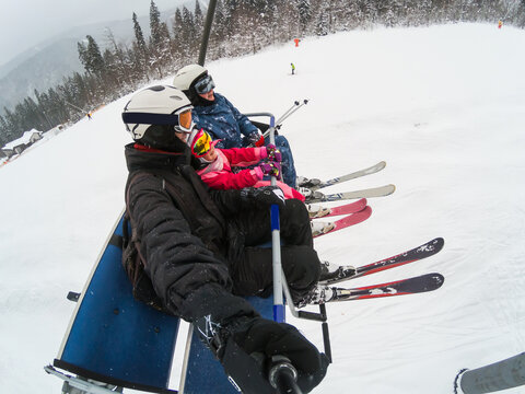 Skiing, ski lift, ski resort - happy smiling family skiers on ski lift making selfie