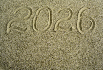 The date 2026 is written on the sea sand. Festive background.