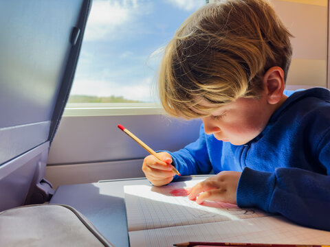 Cute boy on high-speed train writes in the notebook