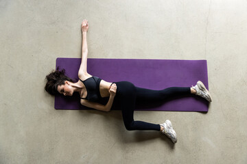 Sporty young woman lying on yoga mat doing sit-ups in gym.
