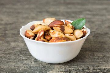 Fresh healthy Brazil nuts in bowl on colored table background. Top view Healthy eating bertholletia concept. Super foods