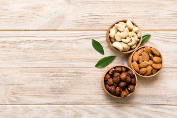 Assortment of nuts in wooden bowl on colored table. Cashew, hazelnuts, walnuts, almonds. Mix of nuts Top view with copy space