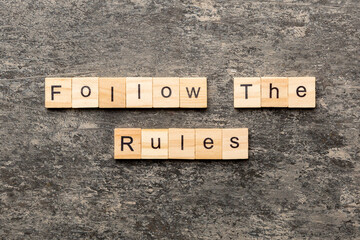 Follow The Rules word written on wood block. Follow The Rules text on table, concept