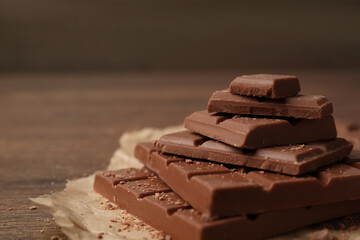 Pieces and crumbs of tasty chocolate on table, closeup. Space for text