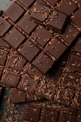 Pieces and shavings of tasty chocolate bars on grey table, flat lay