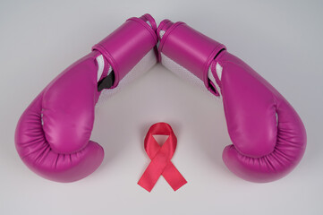 Pink boxing gloves and a pink silk ribbon on a white background. Breast cancer concept. 