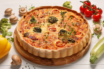 Delicious homemade vegetable quiche and ingredients on white table