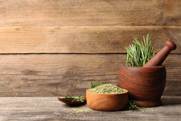 Fresh and dry rosemary on wooden table, space for text