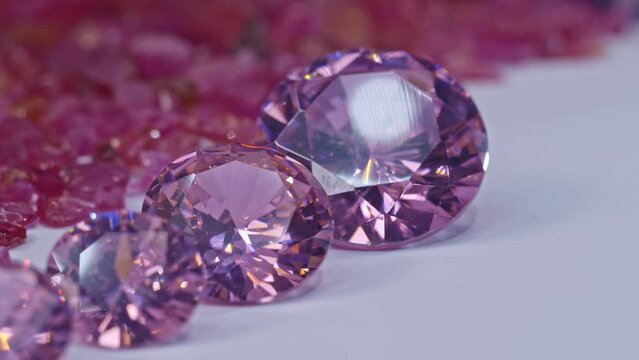 .pink sapphires diamonds in different size and many shape are place in .the middle on a white ground surrounded by uncut raw red garnet stones. .high quality 4K video.