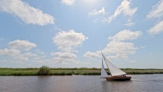 Wooden sailing cruiser keeled over during the annual Three Rivers Race, Norfolk Broads. Captured at the River Bure section on a bright summer day