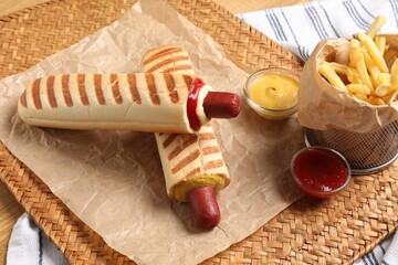Delicious french hot dogs, fries and dip sauce on wicker mat