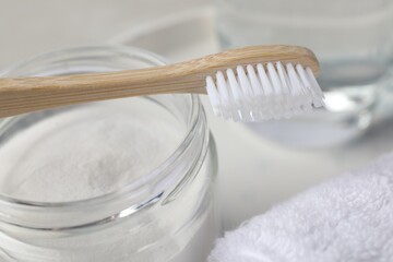 Bamboo toothbrush and jar of baking soda on table, closeup