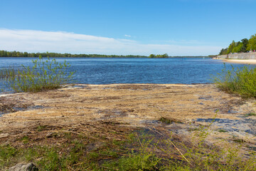 Dirty foam on the bank of the wide Dnieper river (Dnipro) near the beach and embankment