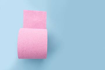 Roll of pink toilet paper on blue background. Personal hygiene products.