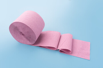Roll of pink toilet paper on blue background. Personal hygiene products.