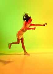 Fototapeta Portrait of emotive beautiful girl, business woman with flying hair running and screaming over acid green color studio background in neon light. Busy day obraz