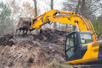 Fototapeta Excavator digging soil. Construction work in countryside, digging soil obraz