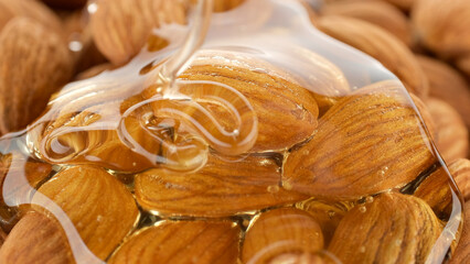 Nuts in honey. Pouring honey on almonds, close up