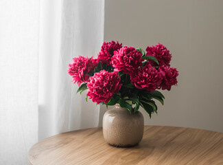Bouquet of peonies in a ceramic vase on a wooden table