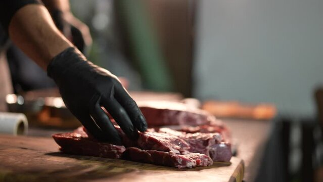 Close up of chef's hands laying out delicious beef steak for grilling. Super slow motion. barbecue or BBQ.