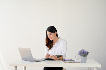 A businesswoman looking at her laptop screen and working on her tasks at her desk