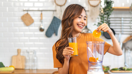 Portrait of beauty healthy asian woman making orange fruit smoothie with blender.young girl preparing cooking detox cleanse with fresh orange juice, vitamin c, in kitchen at home.Diet.healthy drink