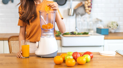 Portrait of beauty healthy asian woman making orange fruit smoothie with blender.young girl preparing cooking detox cleanse with fresh orange juice, vitamin c, in kitchen at home.Diet.healthy drink