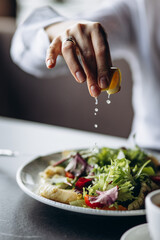 Woman squizing lemon on the salad