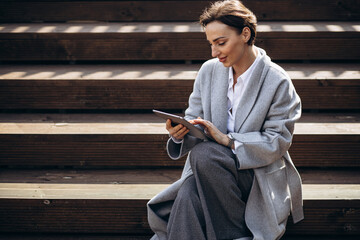 Business woman sitting on stairs and working on tablet