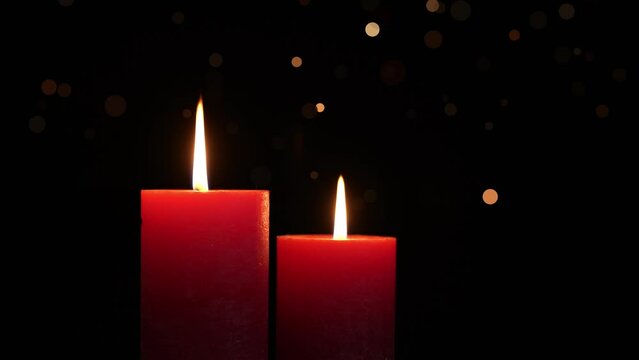 two red burning candlelights slow rotating with shiny bokeh light animation isolated on black background, overlay texture template for festive holiday decoration