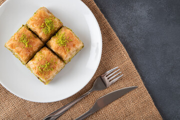 Traditional pistachio baklava in white plate.A plate baklava black background
