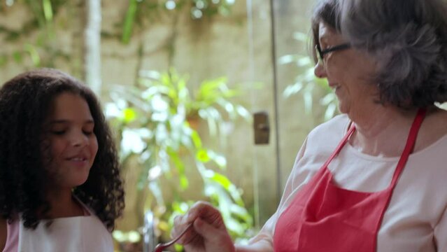 crian&ccedil;a brasileiro provando brigadeiro na cozinha com sua av&oacute; no dia das m&atilde;es