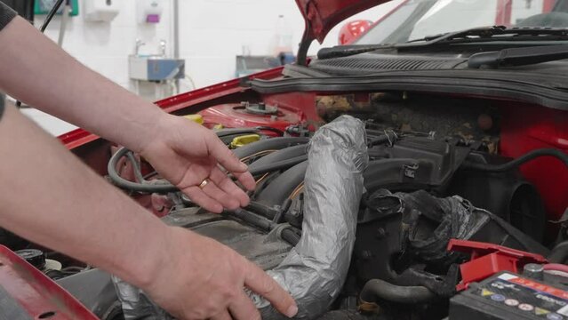 Person checking a car air box and the poor repair carried out using tape