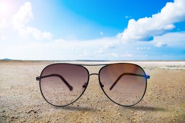 Fototapeta na wymiar New stylish modern sunglasses on beach sand