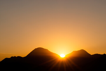 Silhouettes of mountains with an orange color of sunset and sunrise. Forest silhouettes. Mountains landscape.