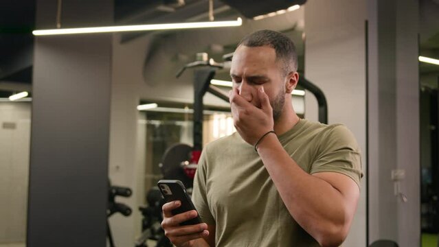 Sad upset stressed shocked loser African American fitness trainer guy sportsman male athlete bodybuilder man lost problem failure phone mobile trouble bad news online difficulties in sport club gym