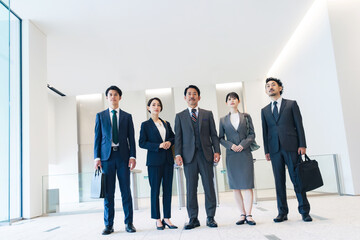 Fototapeta premium Group of smiling Asian business people lining up in office building lobby. Teamwork of business concept.