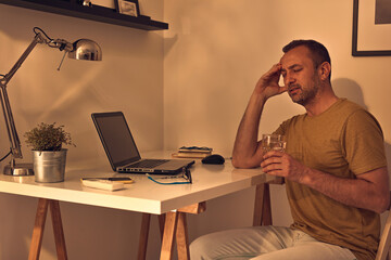 Man exhausted from working on a laptop at home.
