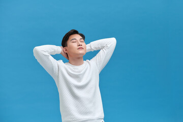 young man relaxing and stretching, arms and hands behind head and neck smiling happy