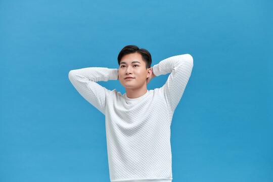 Young Man Relaxing And Stretching, Arms And Hands Behind Head And Neck Smiling Happy