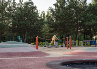 A happy girl at a playground. The girl is playing on net ropes.